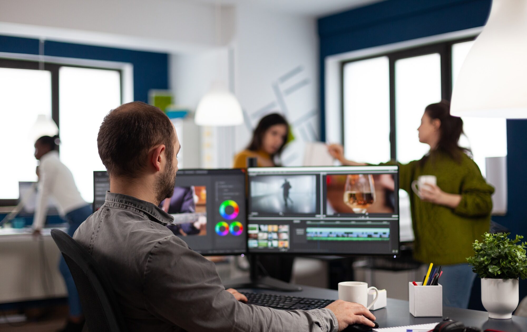 Video editor cuting footage working at film editing montage on computer with dual monitors setup